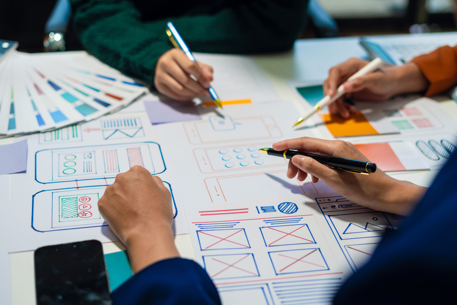 Designers sketching website wireframes with a colour swatch fan